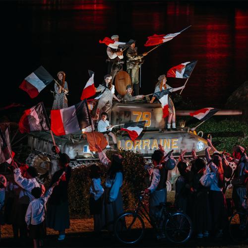 Scène de la Libération avec un char militaire et drapeaux français lors de la Cinéscénie au Puy du Fou.